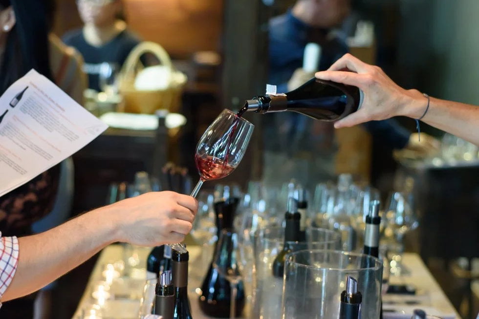 A person pouring wine into a glass at a wine tasting event.